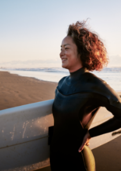 image montrant une femme sur la plage tenant une planche de surf